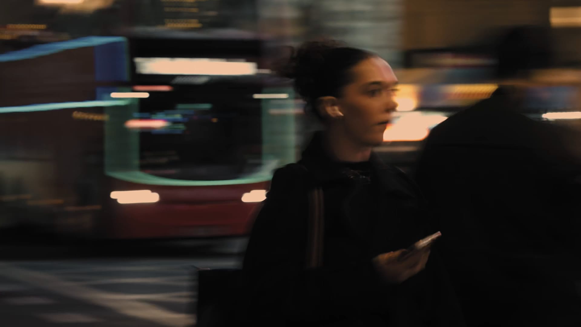 Still from a Sony spec commercial: a woman passing a blurred London bus at dusk