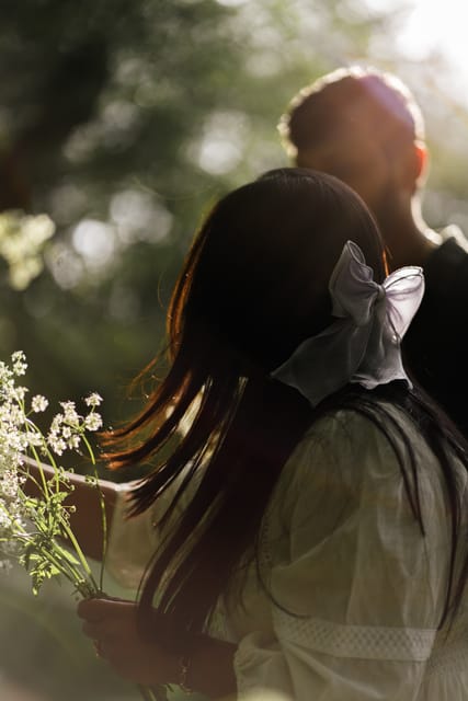 Backlit woman with a white bow among cow parsley
