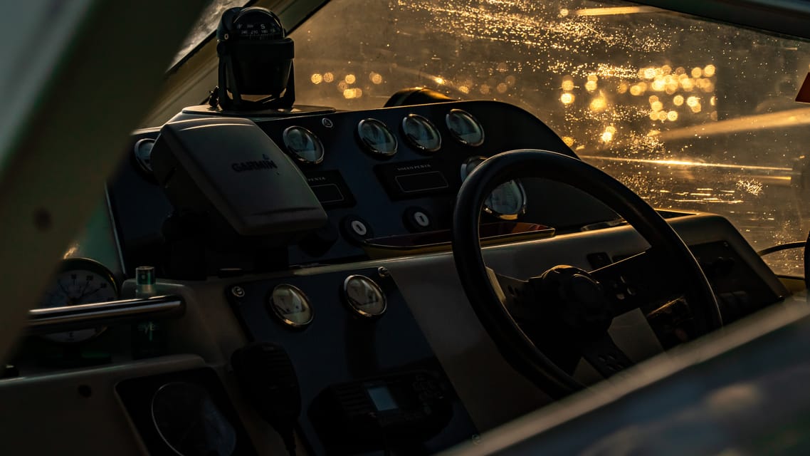 Boat cockpit dials and wheel against sunset bokeh