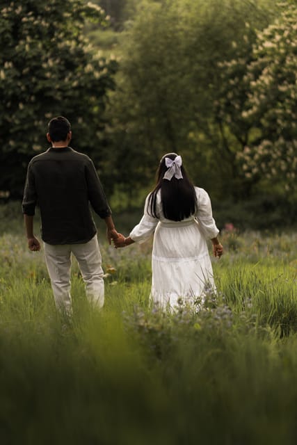 Couple walking hand in hand through a meadow