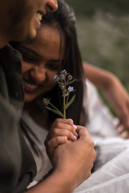 Couple laughing together holding a small flower