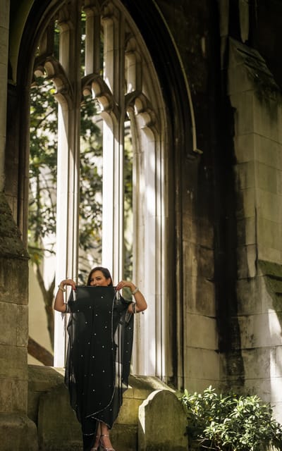 Woman in a beaded black kaftan standing in a gothic ruin