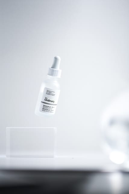 The Ordinary serum bottle floating above an acrylic block