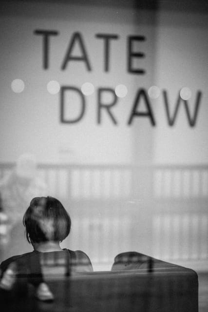Woman beneath large wall lettering, black and white